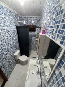 a blue tiled bathroom with a toilet and a sink at Casa inteira II - 2 quartos in Pomerode