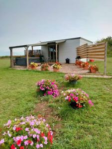 a house with flowers in the yard at Beautiful Wooden tiny house, Glamping cabin with hot tub 3 in Tuxford