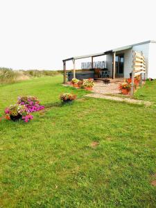 a building with flowers in front of a yard at Beautiful Wooden tiny house, Glamping cabin with hot tub 3 in Tuxford