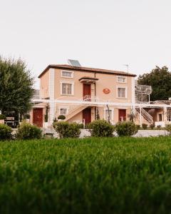 une grande maison rose avec une pelouse devant elle dans l'établissement Ca' Del Conte, à Padula
