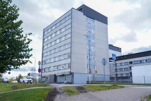 un grand bâtiment blanc dans un parking dans l'établissement Brahenkatu Apartment, à Kajaani