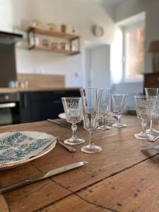 a wooden table with wine glasses and plates on it at Gîte Le carré 1869 in Landas