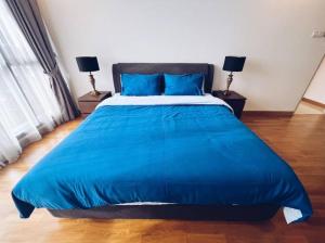 1 cama azul grande en un dormitorio con 2 lámparas en [PROMO]Connected train 2 Bedrooms - Above Mall(25), en Kuala Lumpur
