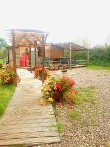 a wooden walkway with flowers in front of a building at Beautiful Wooden tiny house, Glamping cabin with hot tub 2 in Tuxford
