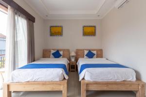 Dos camas individuales en una habitación con ventana. en Rumah Kultur, en Ubud