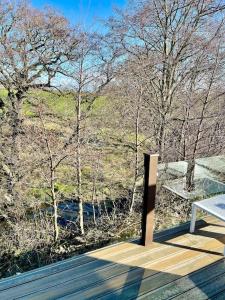 a wooden deck with a bench and trees in the background at Unwind@36 Lodge in Felton