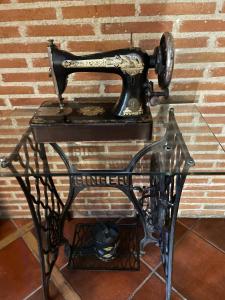 an old sewing machine on a stand against a brick wall at Hotel Arco San Vicente in Ávila