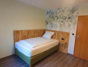 a small bedroom with a bed with a wooden headboard at Der Höfener Garten in Nuremberg