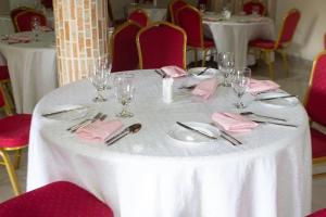 una mesa blanca con cubiertos, servilletas y vasos. en Lou Ralph Hotel, en Accra