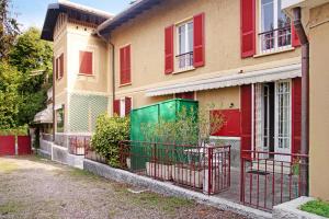 uma casa com janelas vermelhas e um portão verde em Suite in villa con parco em Varese