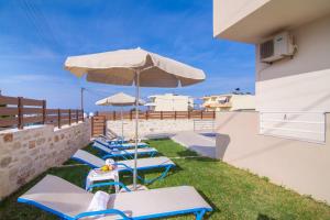 a row of lounge chairs and an umbrella on a yard at 7 bedroom villa with pool, 700m from the beach! in Prínos