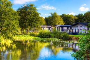 a row of houses next to a river at Lakeside Lodge, Green Hill Farm Holiday Village in Salisbury