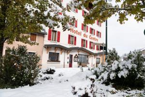 ein Hotelgebäude mit roten Fensterläden im Schnee in der Unterkunft HOTEL RESTAURANT LE CENTRE in Lélex