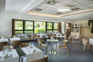 een restaurant met witte tafels, stoelen en ramen bij UNAHOTELS Bologna Fiera in Bologna