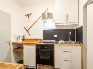 kuchnia z białymi szafkami i czarnym piecem w obiekcie Apartment in Bichlbach near Ski Slopes w mieście Bichlbach +28 zdjęć