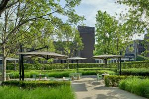 un parque con mesas, sillas y sombrillas en UNAHOTELS Bologna Fiera, en Bolonia