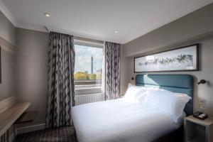 um quarto com uma grande cama branca e uma janela em City Sleeper at Royal National Hotel em Londres