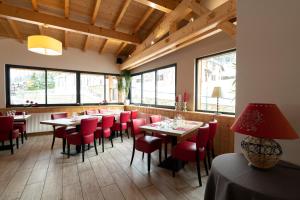 un restaurante con mesas, sillas rojas y ventanas en HOTEL RESTAURANT LE CENTRE, en Lélex