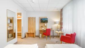 ein Hotelzimmer mit 2 roten Stühlen und einem Schreibtisch in der Unterkunft Hotel Kreuzer in Wedel