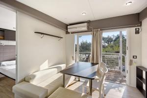 uma sala de estar com uma mesa de jantar e um sofá em Mobile Home Next 229 em Pietra Ligure