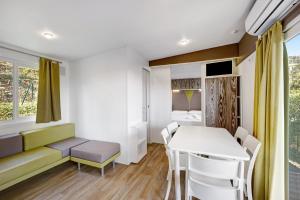 Habitación pequeña con mesa, sillas y cama en Mobile Home Alloro 165, en Pietra Ligure