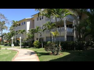 a large apartment building with palm trees and a sidewalk at Delightful Caribbean apartment in Boca Chica in Boca Chica