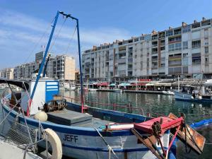 un bateau bleu amarré dans un port de plaisance avec des bâtiments dans l'établissement Studio avec terrasse à deux pas du port, à Toulon