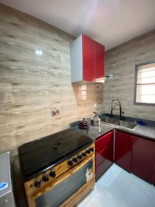 La cuisine est équipée de placards rouges et d'un four avec plaques de cuisson. dans l'établissement Mr Luxury 3 Bedroom Apartment, à Lagos