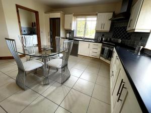 a kitchen with a glass table and chairs in it at Drumbar Lodge in Carterʼs Bridge