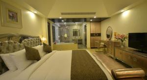 een slaapkamer met een groot bed en een televisie bij Orabella Villas & Suites in Calangute