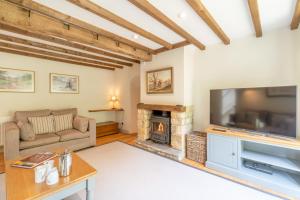 a living room with a large television and a fireplace at Barn End in Chipping Campden