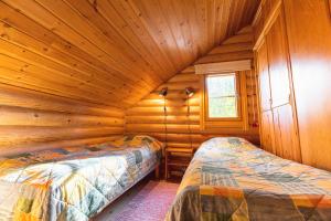 a bedroom with two beds in a log cabin at Taikalevi Apartment in Levi