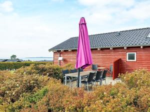 un paraguas rosa sentado en una mesa frente a una casa en 6 person holiday home in Faaborg en Bøjden