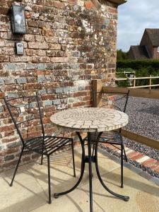 een tafel en twee stoelen naast een bakstenen muur bij The Barrel Room at The Northbrook Arms in Winchester