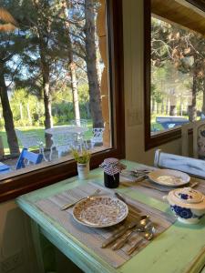 a table with plates and utensils on a table with a window at Cinco Sentidos Hosteria in Lago Meliquina