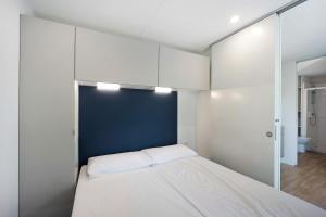皮耶特拉利古雷的住宿－Bungalow Ulivi 148，一间小卧室,配有白色的床和蓝色的墙壁