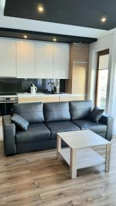 ein Wohnzimmer mit einem schwarzen Sofa und einem Tisch in der Unterkunft Apartament LUXON 4 in Kielce
