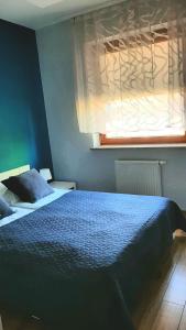 ein Schlafzimmer mit einem blauen Bett und einem Fenster in der Unterkunft Apartament LUXON 4 in Kielce