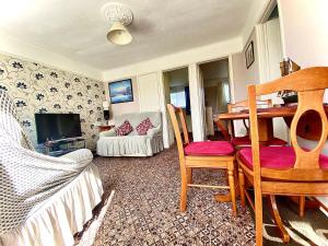 ein Wohnzimmer mit einem Tisch und Stühlen sowie einem TV in der Unterkunft Quiet and Comfy 2- bedroom Holiday Chalet, walk to the beach, Norfolk in Great Yarmouth