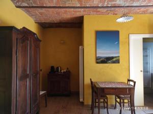 une salle à manger avec une table et un mur jaune dans l'établissement Le camere del Tiglio, à Treiso