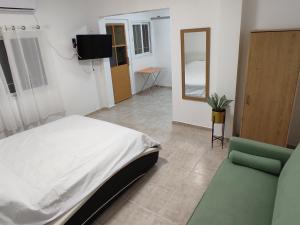 a bedroom with a bed and a tv and a couch at בקצה הקשת - יחידת אירוח מפנקת בירוחם in Yeroẖam