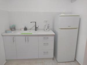 a white kitchen with a sink and a refrigerator at בקצה הקשת - יחידת אירוח מפנקת בירוחם in Yeroẖam