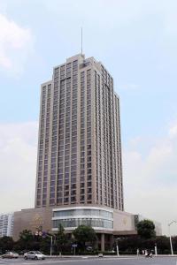 un gran edificio alto con coches estacionados frente a él en Jinling Plaza Changzhou, en Changzhou