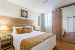 a bedroom with a large bed and a large window at Victory Suites in Juiz de Fora