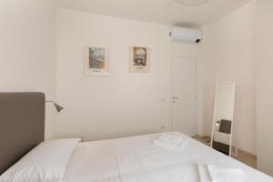 a white bedroom with a white bed and a mirror at Felix 10 in Stresa