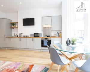 cocina blanca con mesa de cristal y sillas en Apartment 2 - Beautiful 1 Bedroom Apartment Near Manchester en Worsley