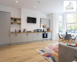 una cocina con armarios blancos y una mesa con sillas. en Apartment 2 - Beautiful 1 Bedroom Apartment Near Manchester en Worsley