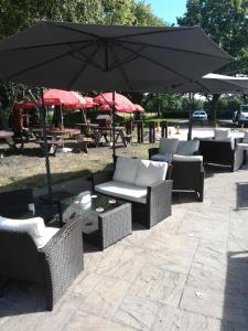 un groupe de chaises et de tables en osier avec un parasol dans l'établissement The Black Swan, à Glazebrook