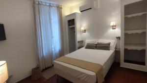 a small bedroom with a white bed and a window at Logis Hôtel & Restaurant du Parc in Gémenos