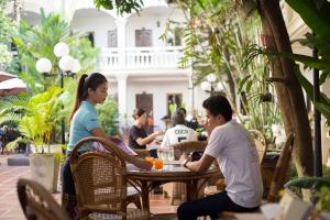 un grupo de personas sentadas en una mesa en un restaurante en Mali Namphu Hotel en Vientián